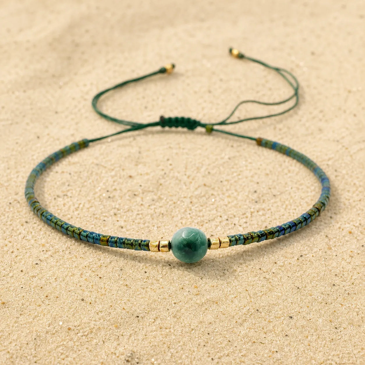 Rocailles Armband grün auf hellem Sand