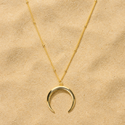 Doppelhorn Halskette Gold mit offenem Mond Anhänger auf hellem Sand