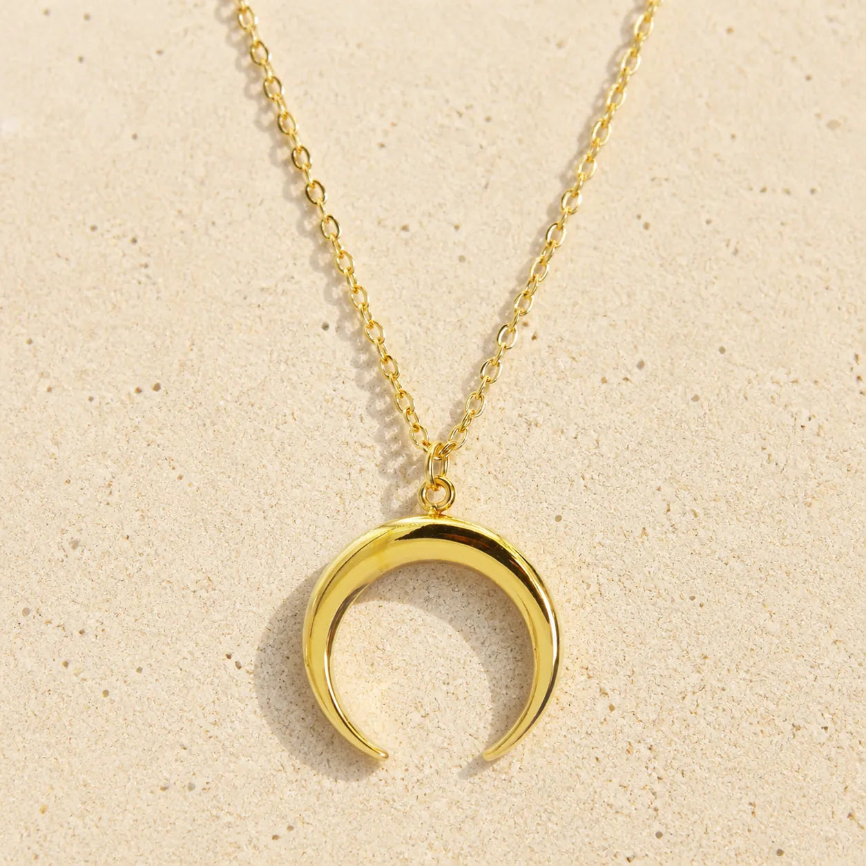 Double horn chain gold on light sand