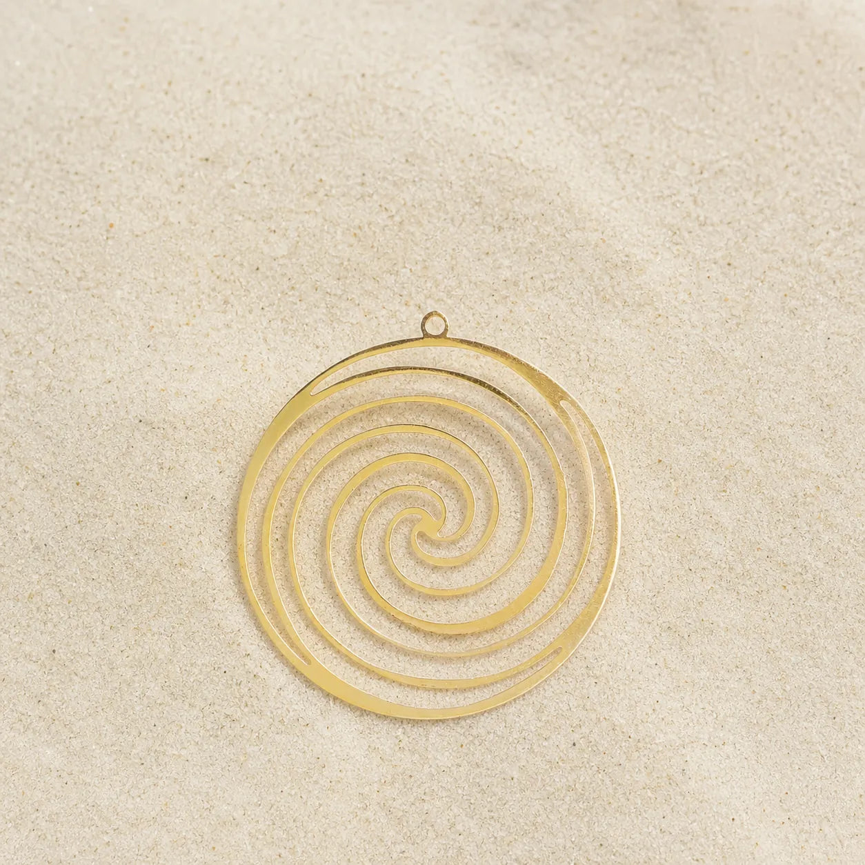 Spirale Kettenanhänger Gold auf hellem Sand