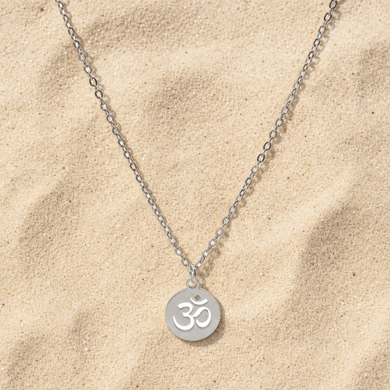 OM Kette Silber auf hellem Sand