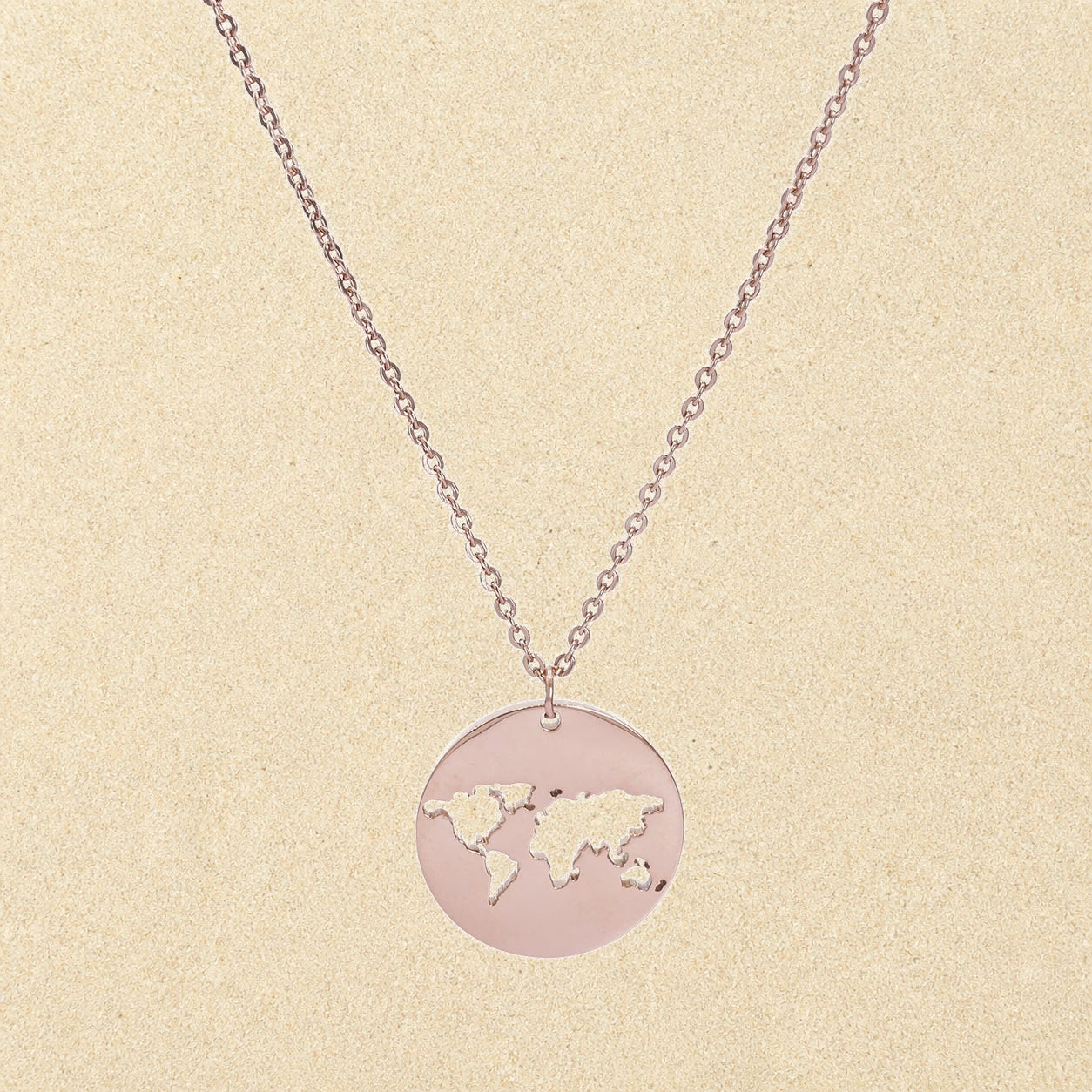 World Map Necklace Rose Gold on light sand