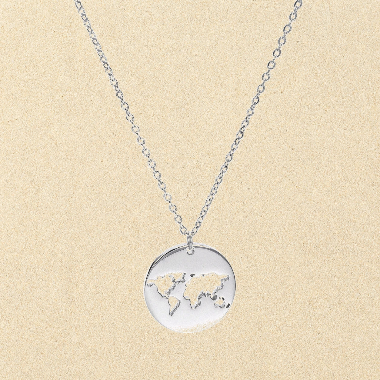 World Map Necklace Silver on light sand