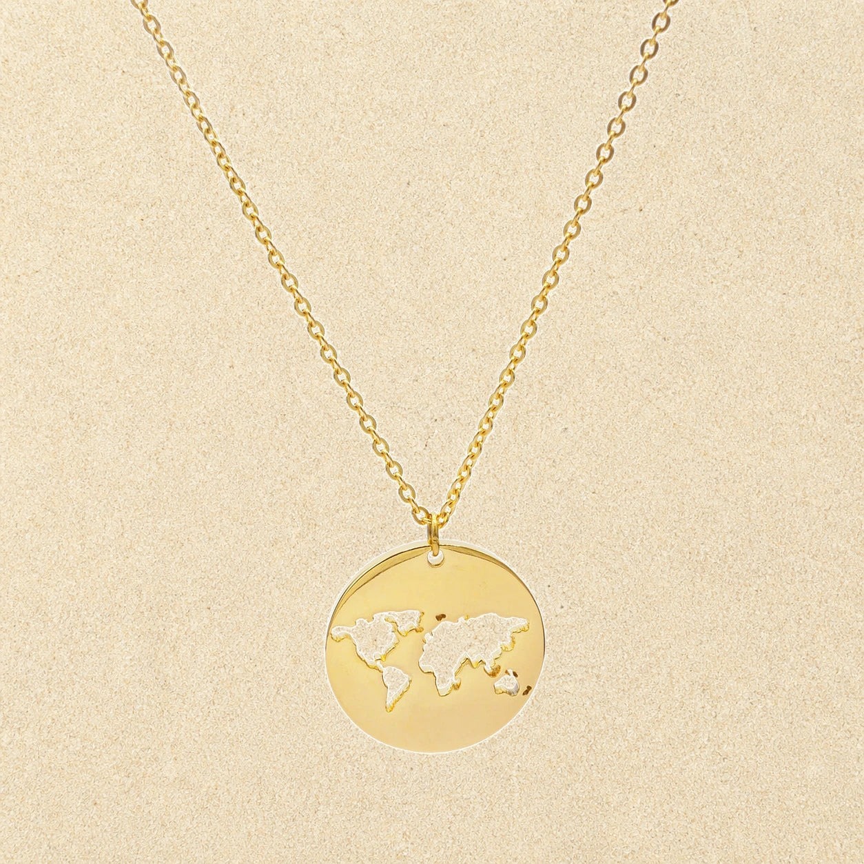 World Map Necklace Gold on light sand